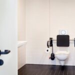 Auch im Besucher-WC sind die barrierefreien Lösungen von HEWI verbaut, wie etwa die Kombination aus Rückenstütze und Stützklappgriff, die genau an die Bedürfnisse von motorisch eingeschränkten Menschen angepasst ist.