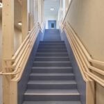 Bodenbelag, Der in den Fluren und Treppenhäusern für den Bodenbelag gewählte Blauton („Dusty Blue“) ergänzt sich ideal mit den Holzelementen und Sichtbetonflächen.