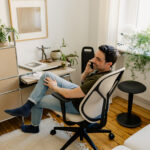Eine telefonierende Person, sitzend auf einem beigen Bürostuhl der Marke Sedus. Die Person befindet sich vermutlich im Homeoffice
