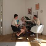 Drei Personen, an einem Tisch sitzend, unterhalten sich interessiert über ein Magazin