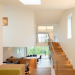 Innenansicht Atelierhaus: Unten zu sehen sind Büroräume, ein Treppenaufgang aus Holz zeigt den Weg in das erste Stockwerk